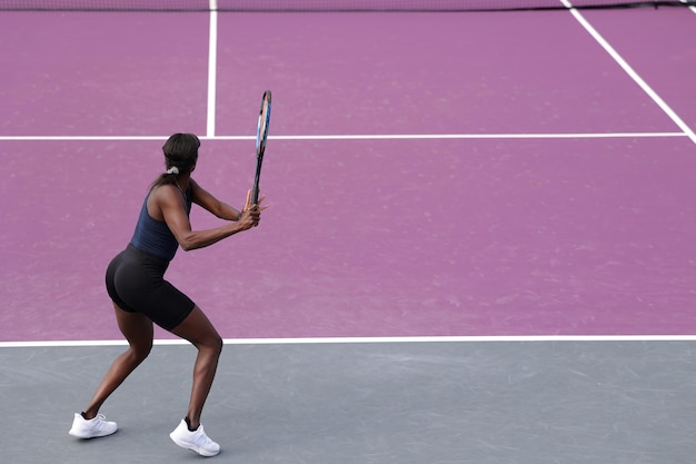 African American female tennis player in action on the court on a sunny day