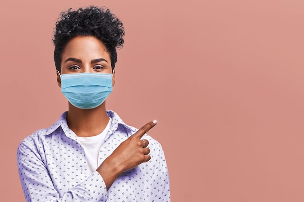 African American Female Wearing Respiratory Mask Shows Something at Blank Space