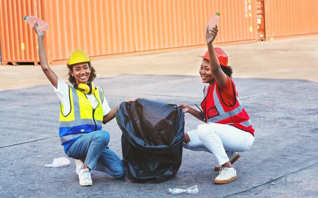 ゴミ袋を持っているアフリカ系アメリカ人の職長の手とプラスチックごみを置くパートナーシップ