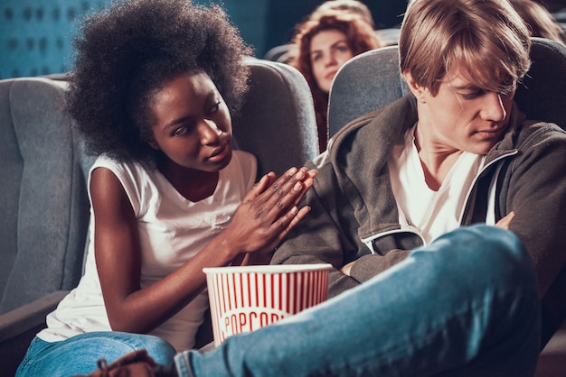 Photo african american girl apologizes to frustrated guy in cinema