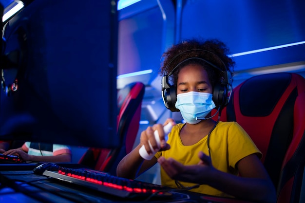 African american girl disinfecting hands and headset before playing video games on computer