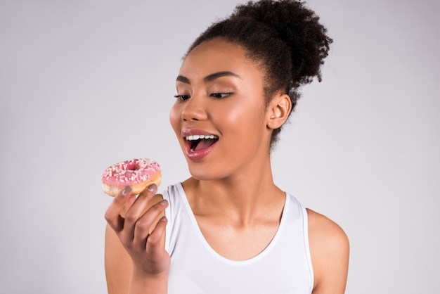 African American girl eating donut isolated.