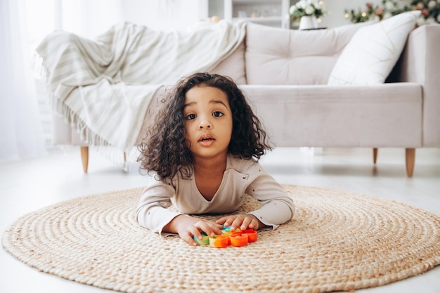 ストレスを和らげるボタンを押すポップおもちゃで遊んで家の床にアフリカ系アメリカ人の女の子