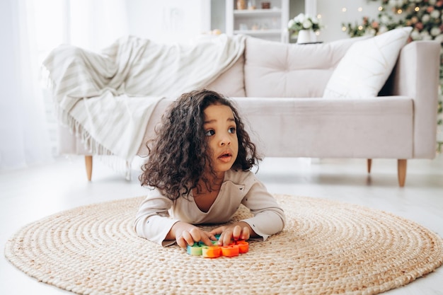 ストレスを和らげるボタンを押すポップおもちゃで遊んで家の床にアフリカ系アメリカ人の女の子