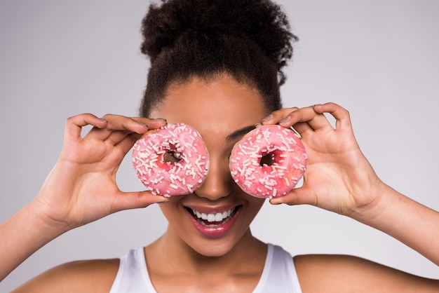 Ciambella della holding della ragazza dell'afroamericano isolata.