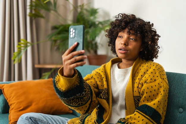 African american girl holding smartphone having video chat female blogger chatting with best friends