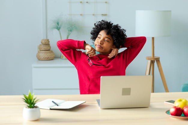 Photo african american girl at home office relaxing stretching hands and body taking break from work on