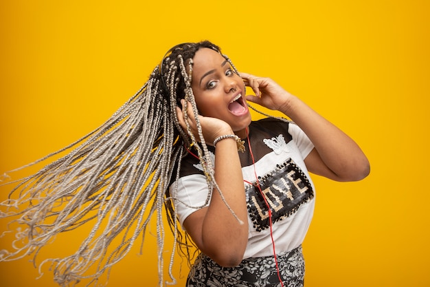 African American girl listening to music on a headphones on yellow