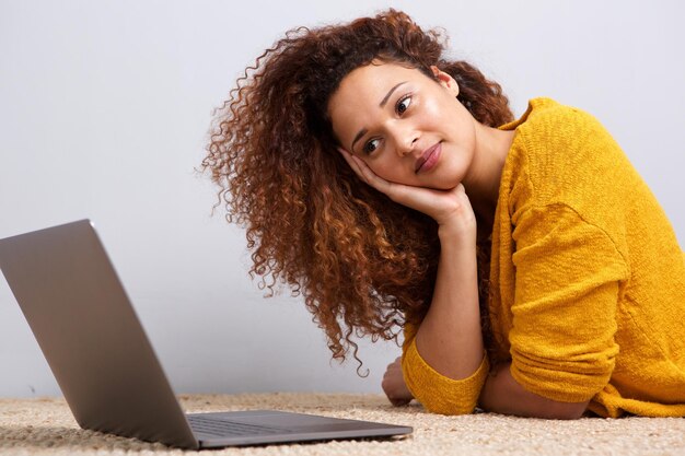 African american girl lying on floor looking at laptop computer screen