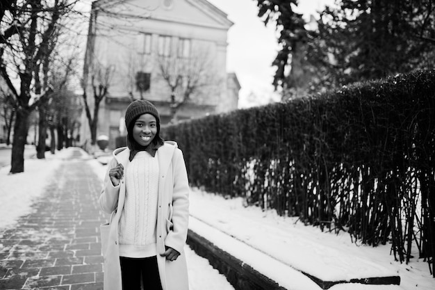 African american girl in red hat and pink coat at street of city on winter day