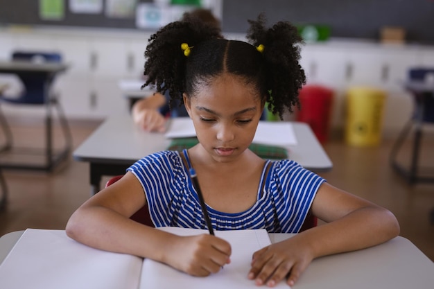 African american girl studying while sitting on her desk in the class at school