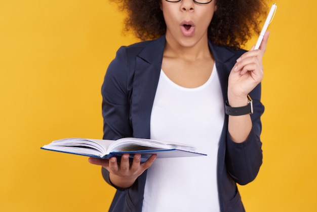 African american girl taking notes on yellow background.