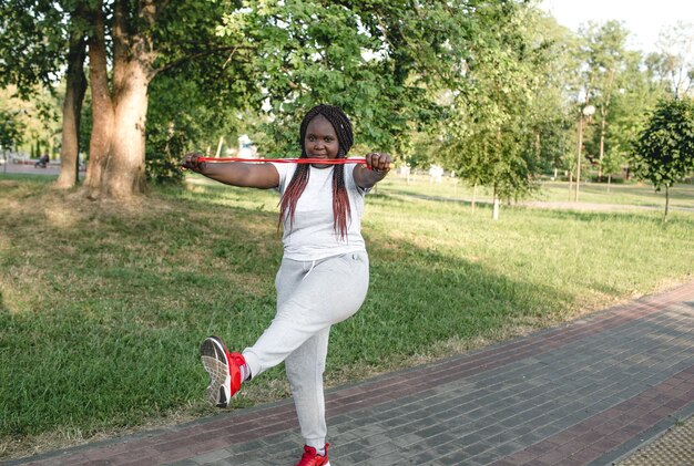 An African-American girl trains in an outdoor park with a rope doing exercises.