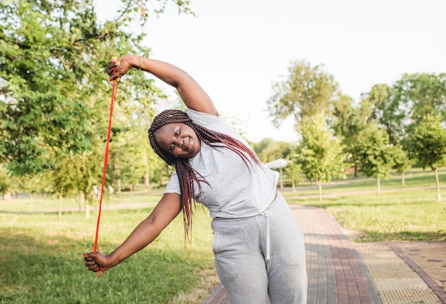 An African-American girl trains in an outdoor park with a rope doing exercises.