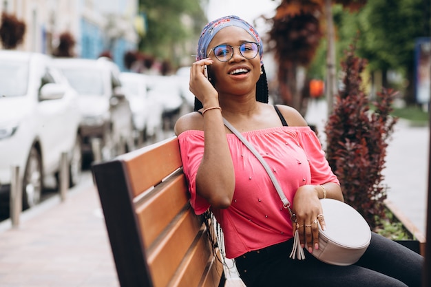 African american girl using her mobile phone while sitting on wooden bench