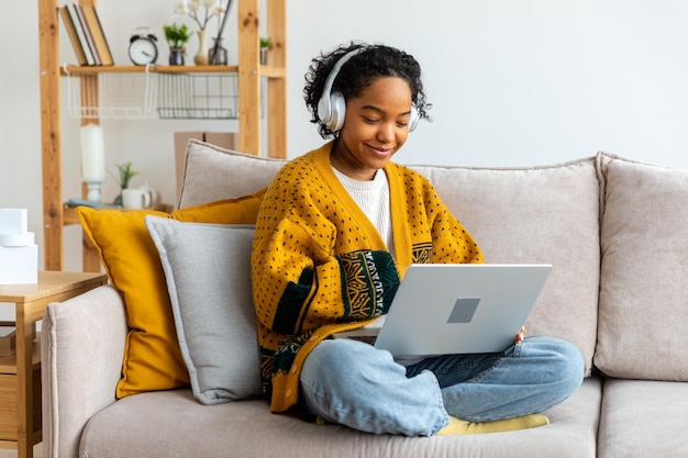 집에서 노트북을 사용하는 아프리카계 미국인 소녀는 화면 입력 채팅 읽기 쓰기를 보고 있습니다.