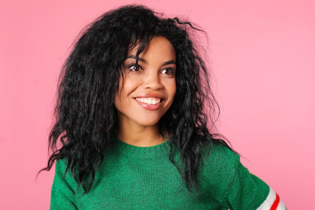 African American girl with long messy raven black hair in a green dress is laughing and looking right at the camera lens