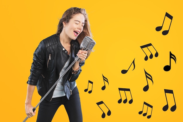 Photo african-american girl with microphone singing against color background