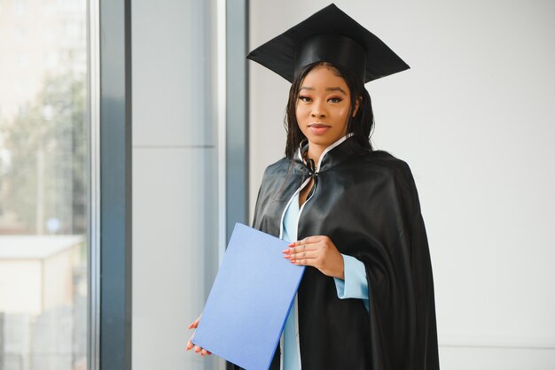 African American graduate holding diploma.