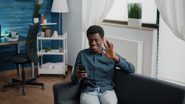 African american guy greeting colleagues or family while talking on online video conference call. Working from home remote worker in distance communication chat, learning and connecting