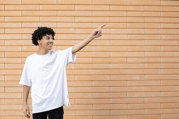 African American guy looking and pointing his finger to the right at the copy space