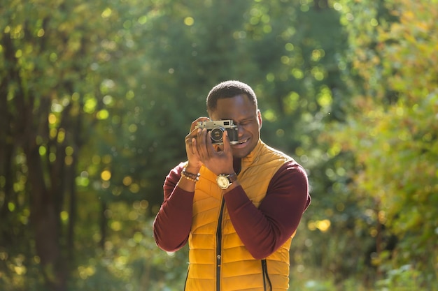 African american guy photographer taking picture with vintage camera on city green park leisure activity diversity and hobby concept