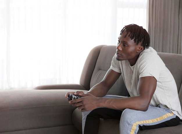 African american guy playing video game with joystick at home