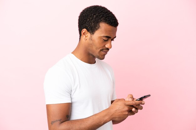 African American handsome man on isolated pink background sending a message or email with the mobile