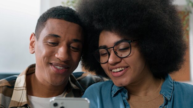 African american happy couple boyfriend girlfriend husband wife using smartphone browsing mobile