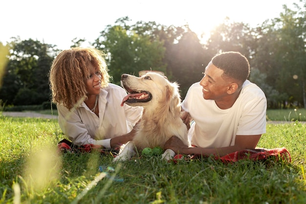 Photo african american happy couple lie together with dog in park in summer