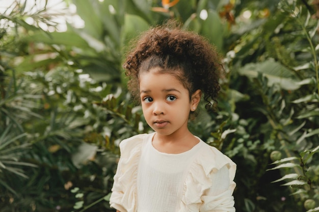 African American happy little girl against the background of decorative leaves in the garden
