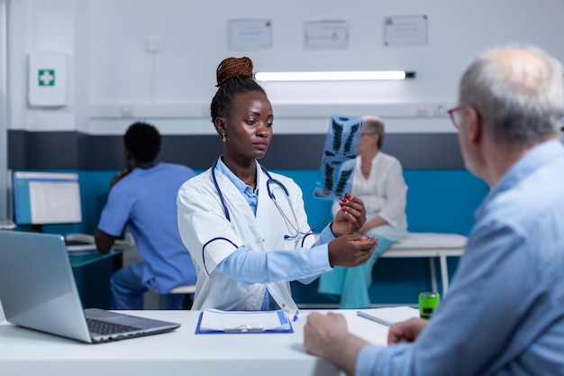 African american healthcare facility radiology specialist reviewing x-ray image scan and analyzing imaging results. Radiology expert examining radiography scan image and concluding diagnostic based on