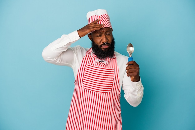 African american ice cream maker man holding an ice cream scoop isolated on blue background being shocked, she has remembered important meeting.