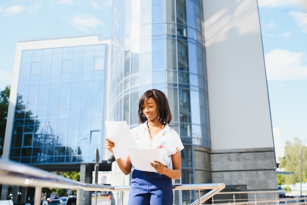 African American job seeker keeping a folder with CV in her hands standing against office building