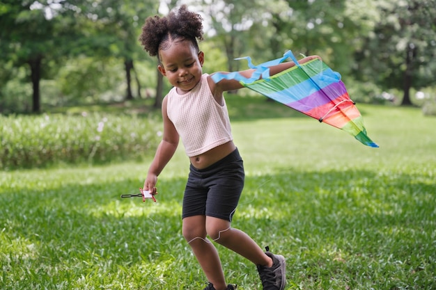 アフリカ系アメリカ人の子供の女の子が公園で凧を再生します