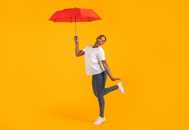 African american lady in casual posing with red umbrella studio