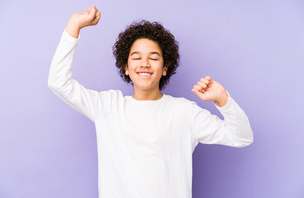 African american little boy isolated celebrating a special day, jumps and raise arms with energy.