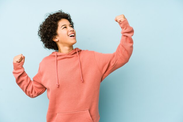 African american little boy isolated raising fist after a victory, winner concept.