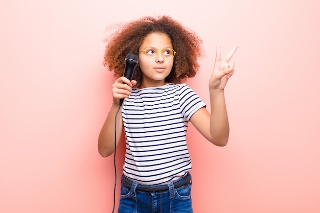 African american little girl  against flat wall with a microphone