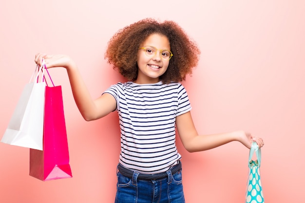 African american little girl  against flat wall with shopping bags