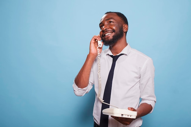 African american male adult making a phone call on a landline Smiling businessman on an analogue telephone phone chatting away A contemporary individual having fun and taking calls