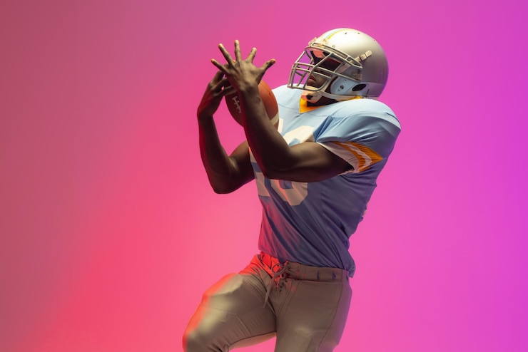 Photo african american male american football player holding ball with neon pink lighting