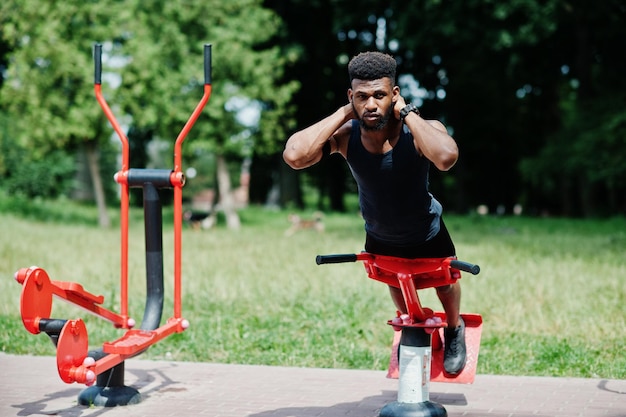 Афро-американский спортсмен-спортсмен с бегущим спортивным чехлом для мобильного телефона, выполняющий упражнения на уличных тренажерах