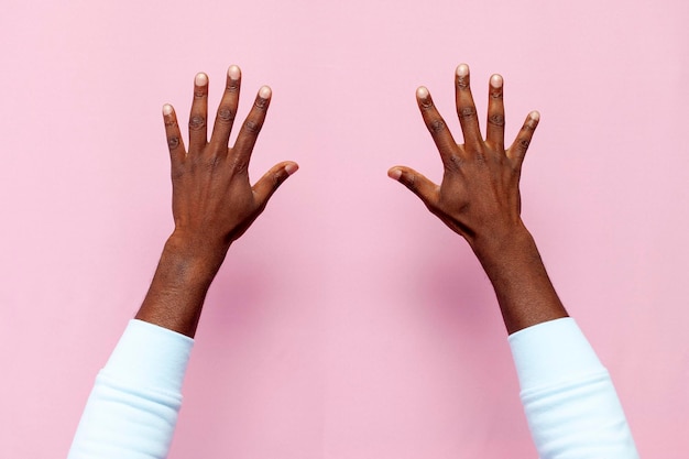 ピンクの孤立した背景のクローズアップ手に手のひらの外側からアフリカ系アメリカ人の男性の手