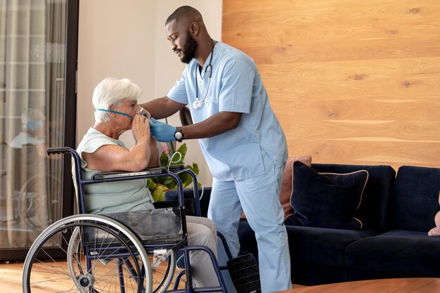 African american male health worker putting oxygen mask on caucasian senior woman on wheelchair