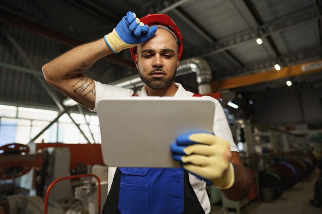 African american male manager in electric cable warehouse holding digital tablet