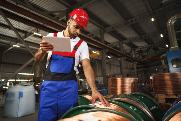 African american male manager in electric cable warehouse holding digital tablet