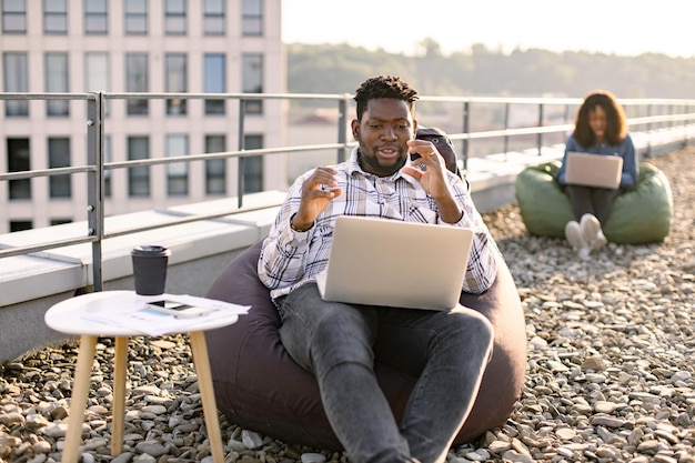 African American male person in casual clothing gesture at laptop camera