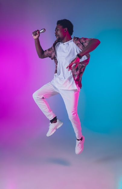 African-american male singer portrait isolated on gradient studio background in neon light