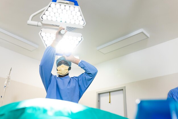 Photo african american male surgeon adjusting light before operation in operating theatre, copy space. surgery, hospital, medical and healthcare services.